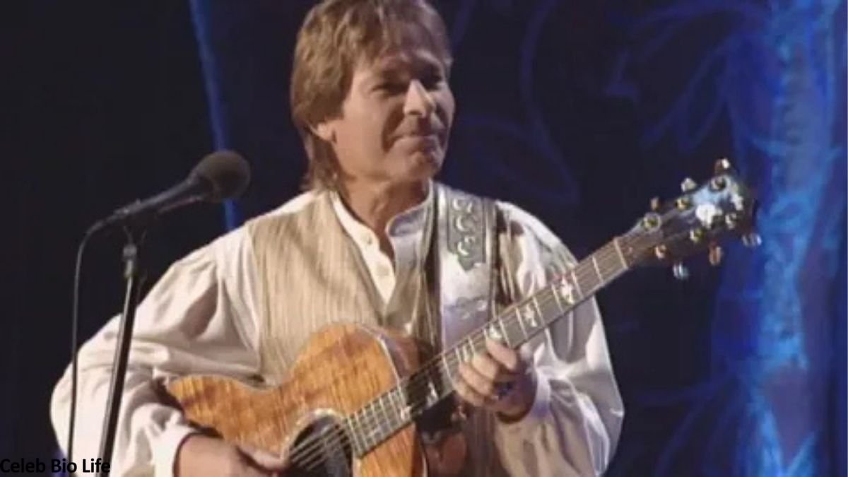 John Denver playing acoustic guitar on stage